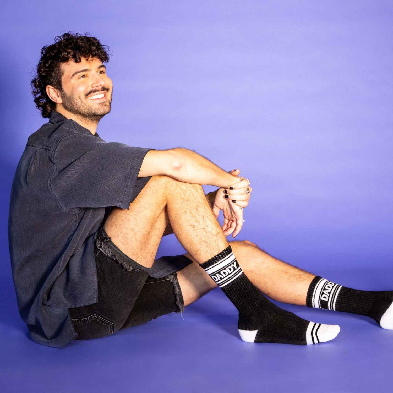 A man wearing a pair of black and white crew socks that read "daddy."