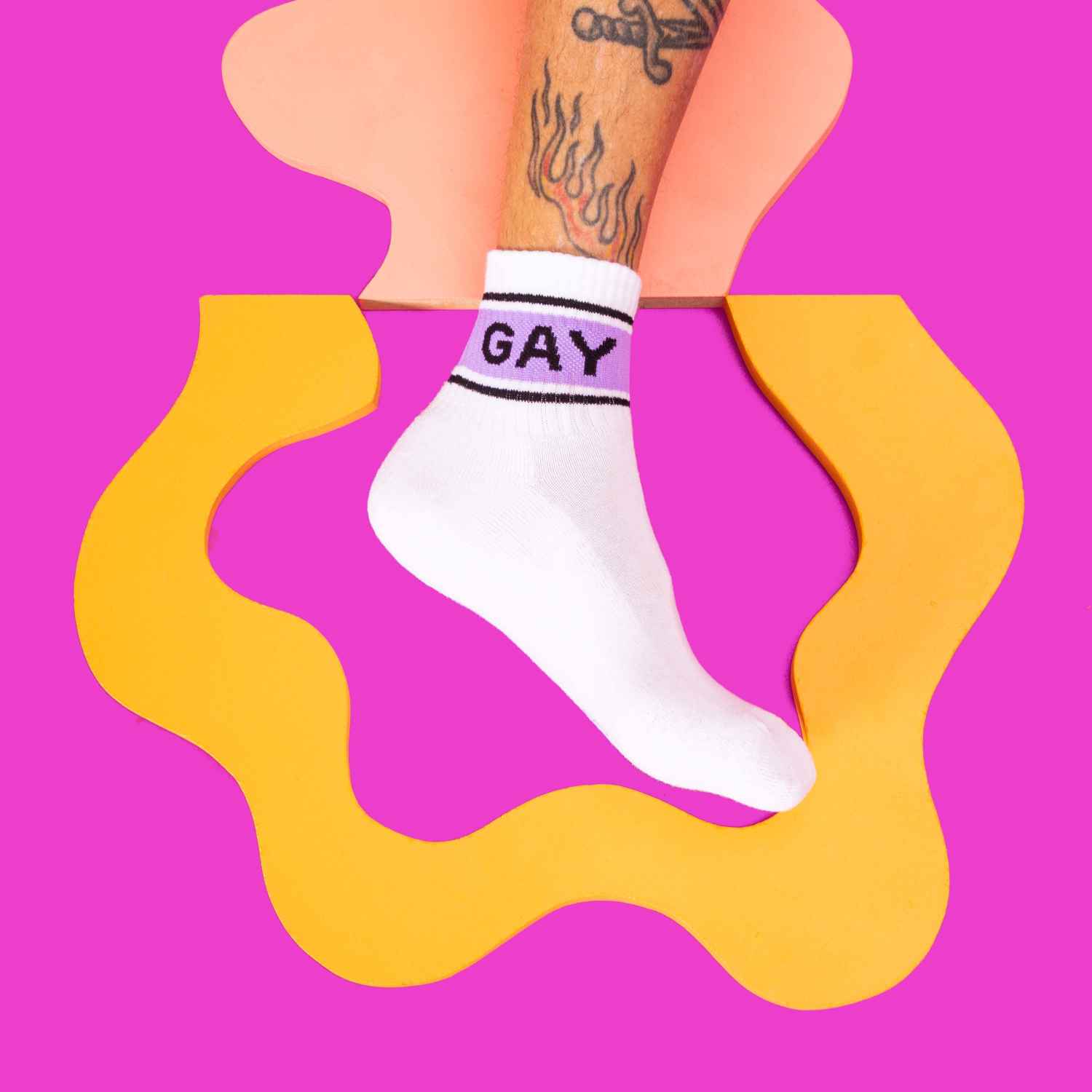 A white and purple quarter-crew sock against a vibrant pink and yellow that read "Gay" with the Gumball Poodle logo along the arch.