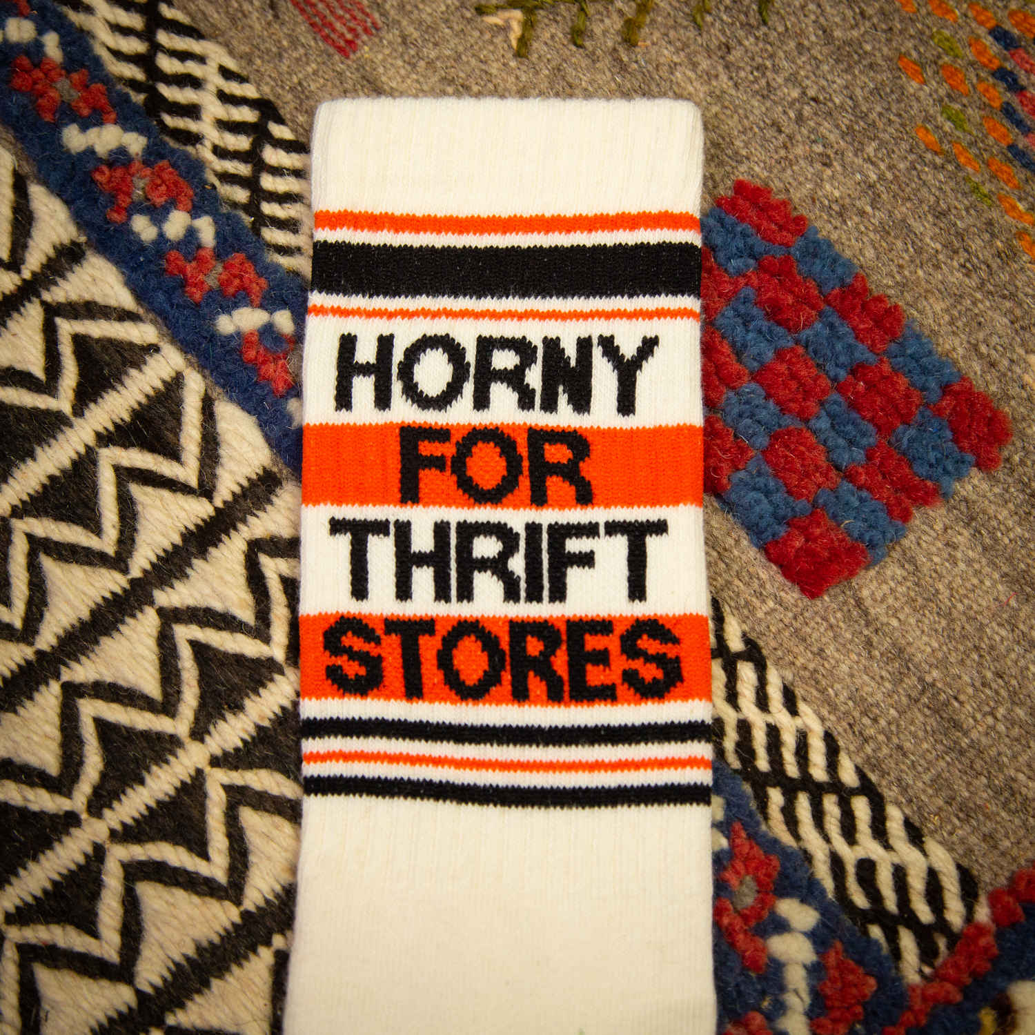 An off-white and red crew sock that read "horny for thrift stores."