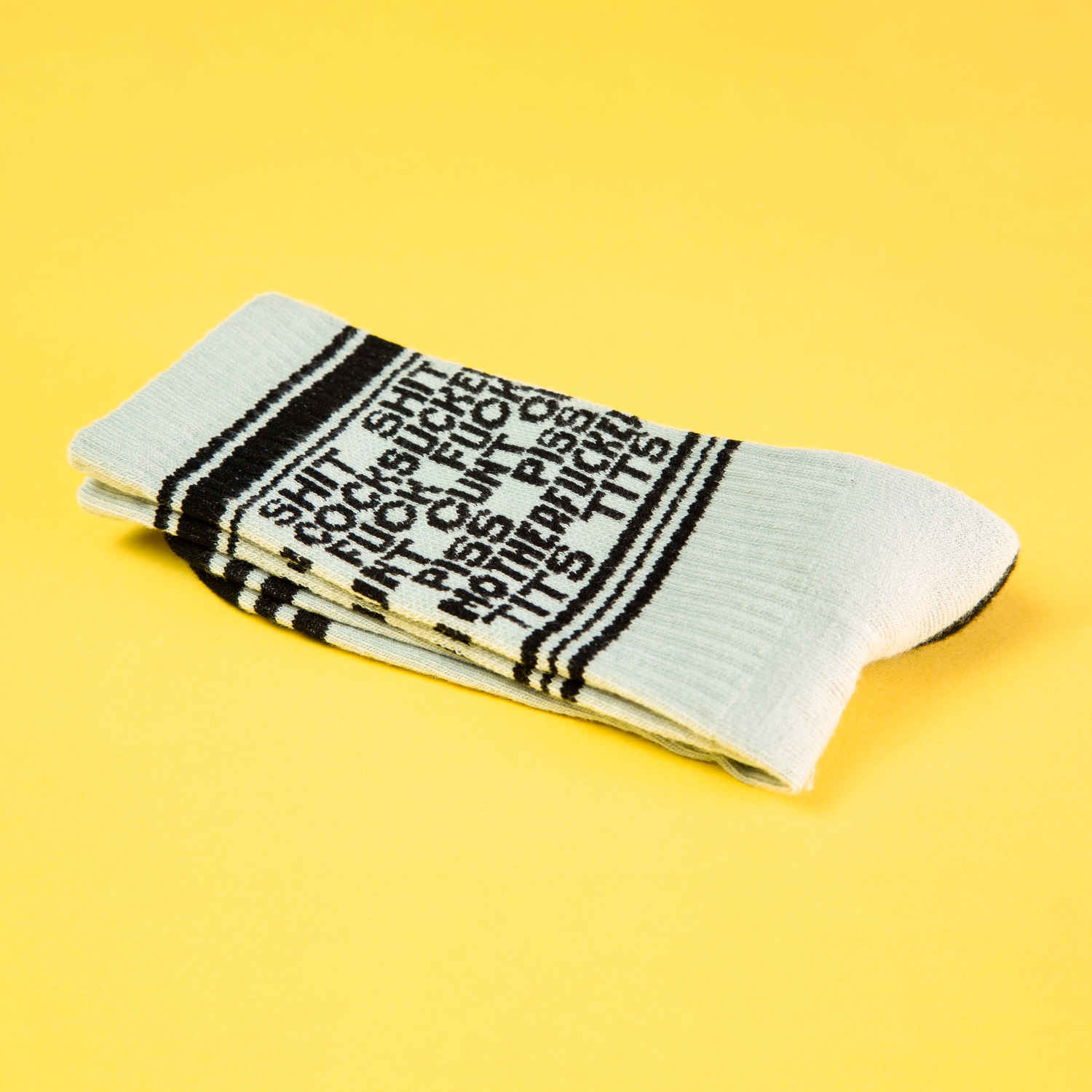 A pair of folded grey and black crew socks that read "shit cocksucker fuck cunt piss motherfucker tits" repeatedly.
